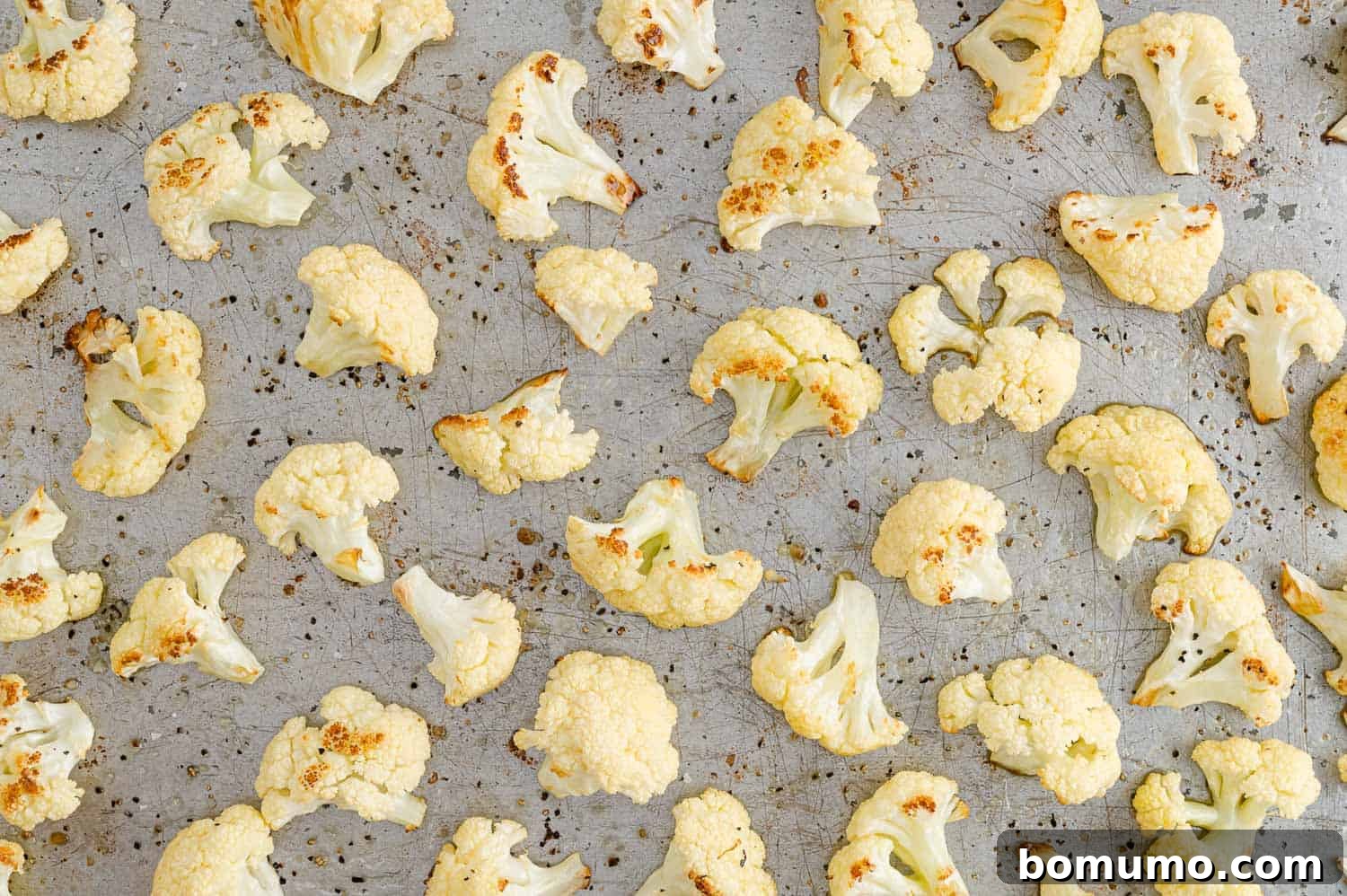 Perfectly Crispy Roasted Cauliflower 12 Roasted cauliflower, golden brown and slightly charred, on a baking sheet.