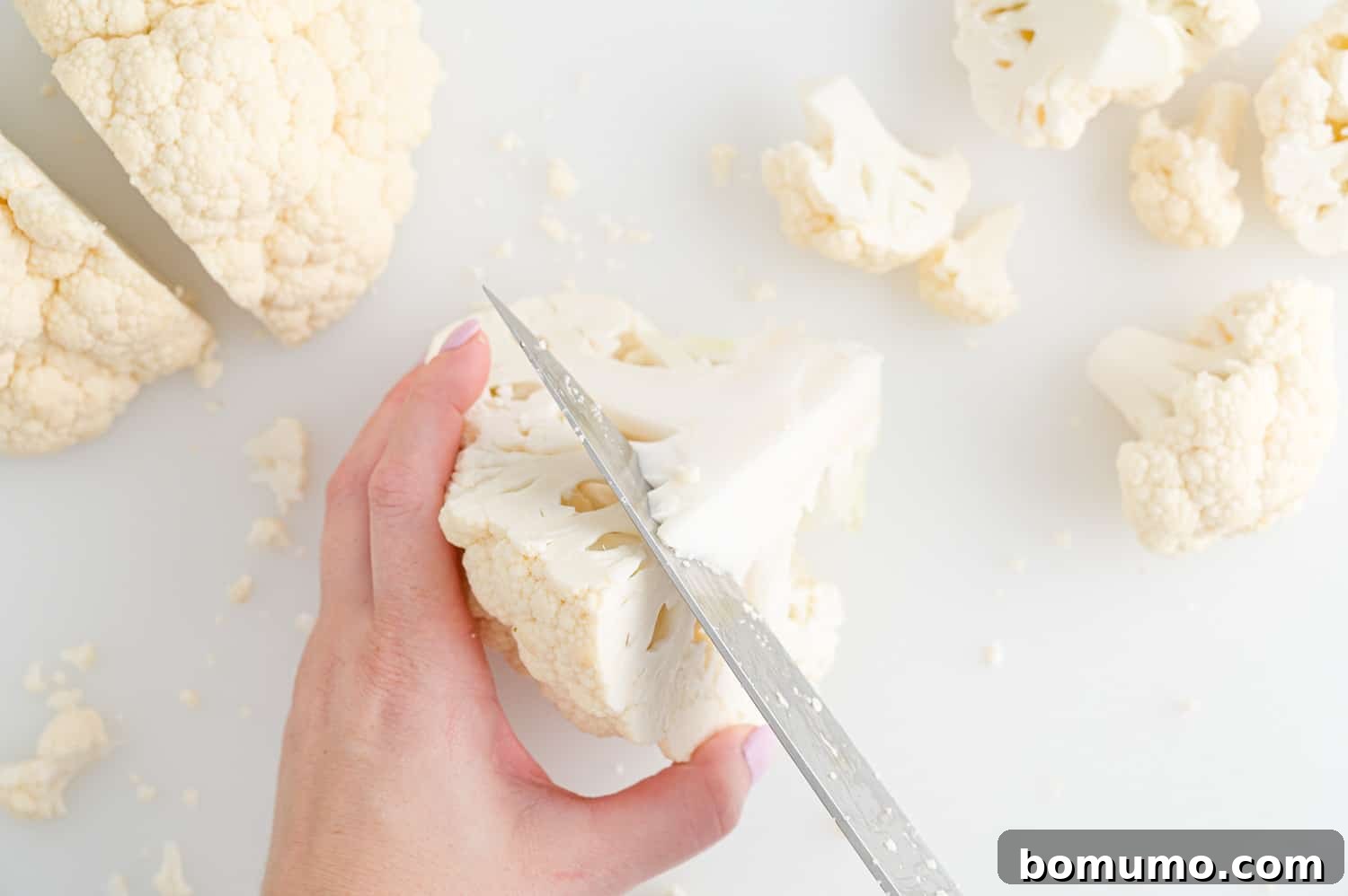 Perfectly Crispy Roasted Cauliflower 6 Core of cauliflower being precisely cut out of a quarter of a head of cauliflower.