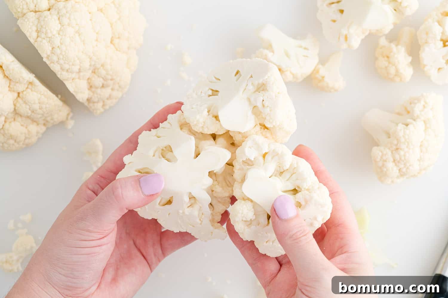 Perfectly Crispy Roasted Cauliflower 7 Large piece of cauliflower being broken into smaller, bite-sized florets.