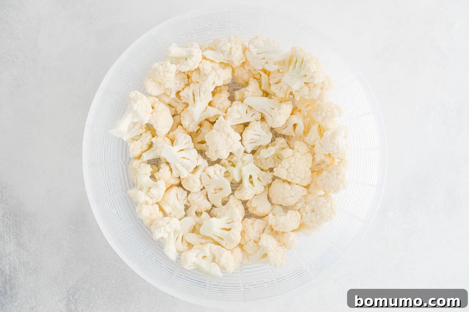 Perfectly Crispy Roasted Cauliflower 9 Cauliflower florets draining in a strainer after washing.