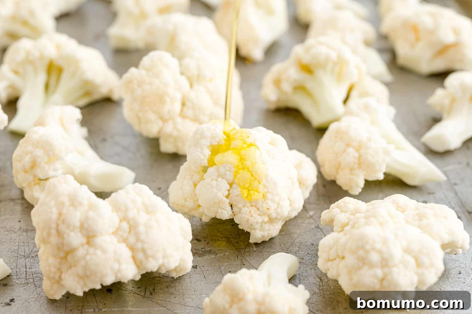 Perfectly Crispy Roasted Cauliflower 10 Olive oil being poured over cauliflower florets in a bowl.