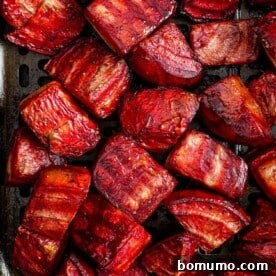 Cooked beets in an air fryer basket, showing their slightly crispy edges and rich color.