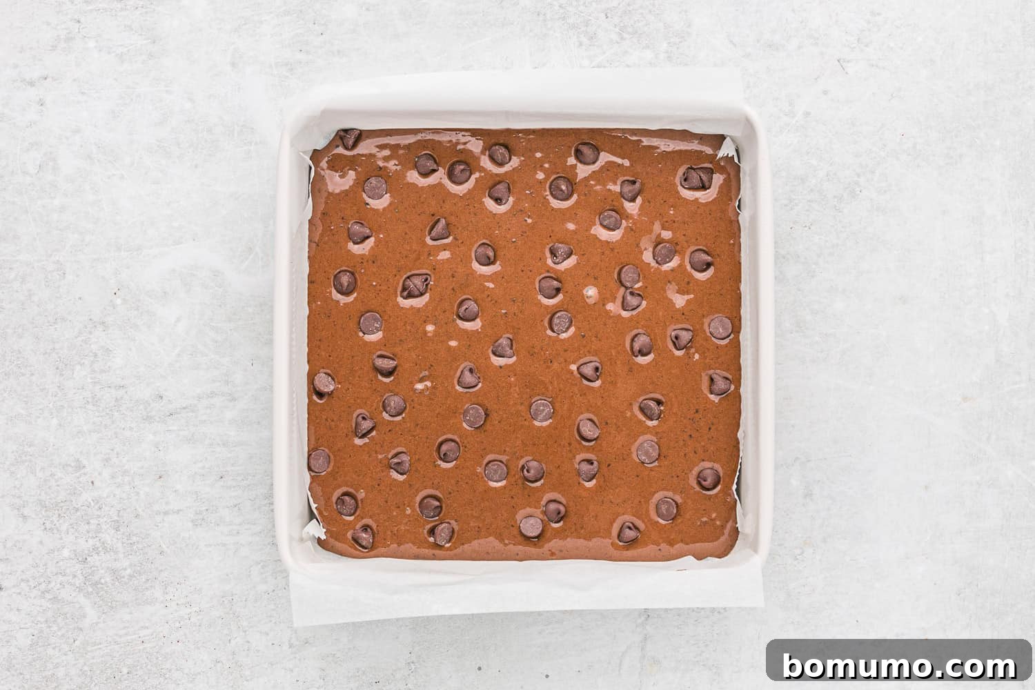 Black bean brownie batter in a pan, topped with additional chocolate chips before baking.