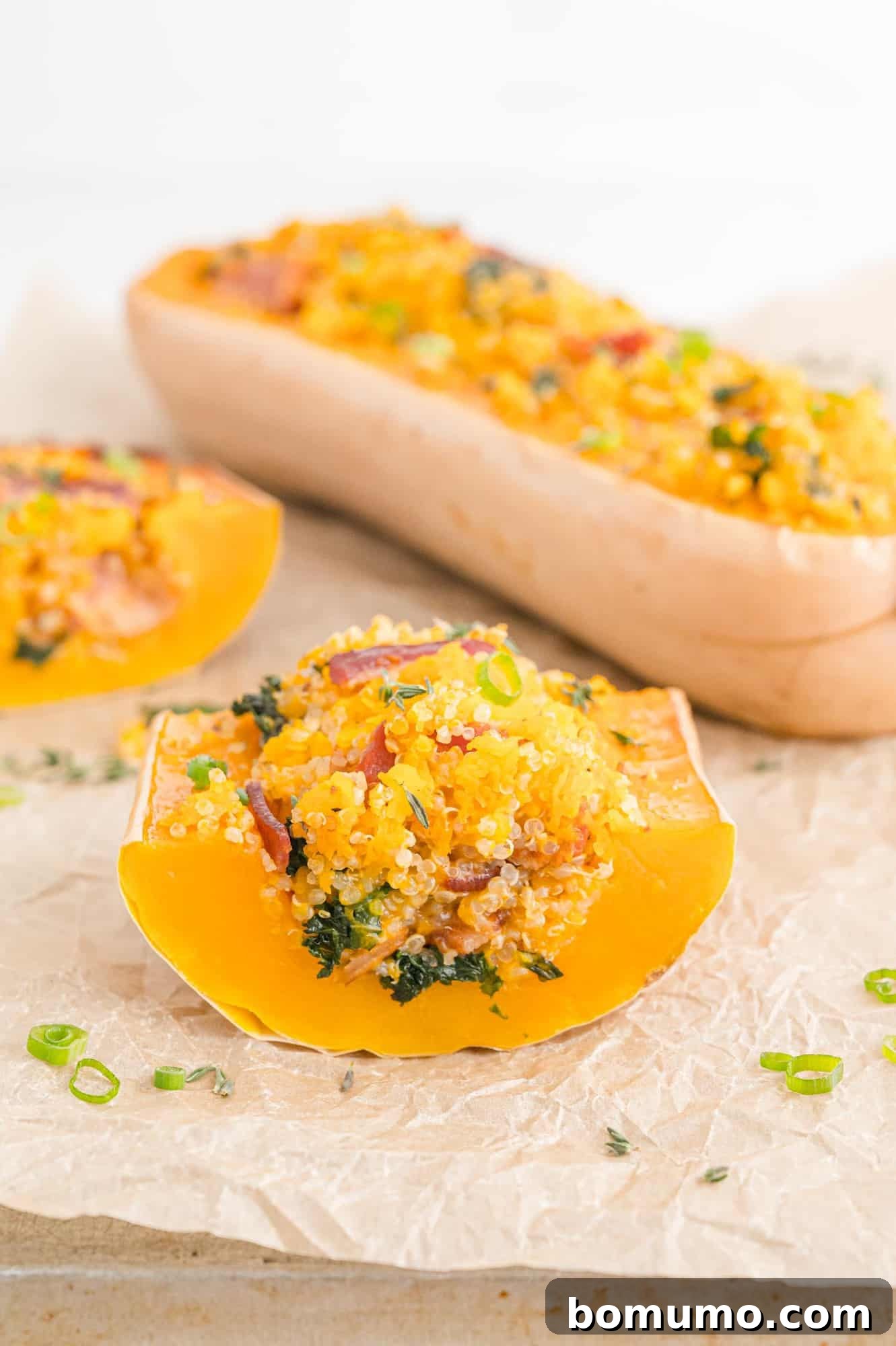 Stuffed butternut squash cut to show filling of quinoa, bacon, kale.