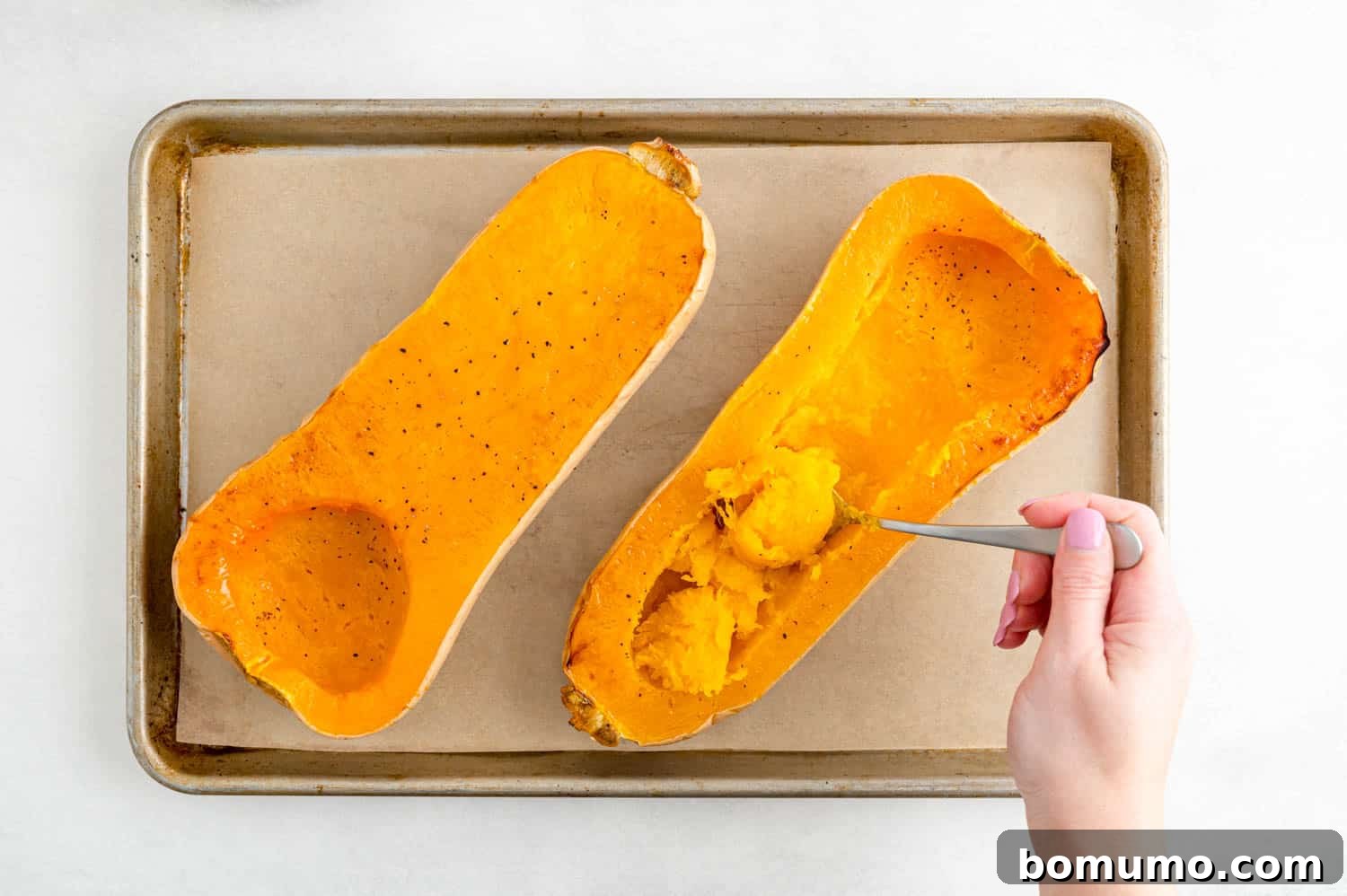 Squash flesh being scooped out.