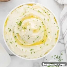 Creamy Instant Pot mashed potatoes in a white serving bowl, topped with a pat of melting butter.