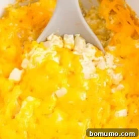 A spoon scooping out cheesy potatoes from a slow cooker, showing the creamy, delicious texture.