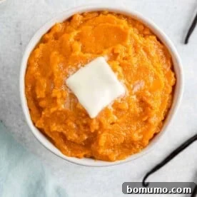 Vanilla bean mashed sweet potatoes in a round bowl, garnished with fresh vanilla bean pods.
