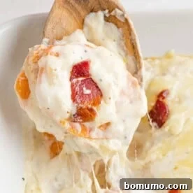 A spoonful of scalloped sweet potatoes with bacon, showing layers of creamy potato and crispy bacon.