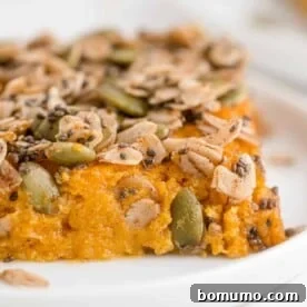A slice of healthy sweet potato casserole, topped with a crunchy mixture of chia seeds, oats, and pepitas.