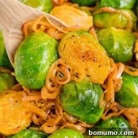 Flavorful smoky Brussels sprouts with shallots, presented on a wooden spoon.