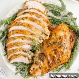 Herb roasted turkey breast, half sliced, half not sliced, on a platter, ready to be served.