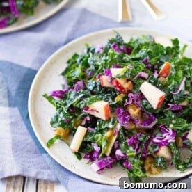 A vibrant kale salad tossed with crisp apples and golden raisins, a perfectly tangy and sweet combination.