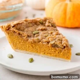 A slice of pumpkin pie with a delightful streusel topping, served on a pristine white plate.