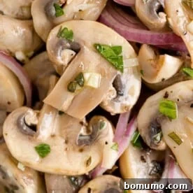 A close-up view of richly marinated mushrooms, glistening with flavorful herbs and spices.