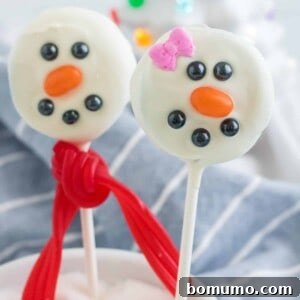 Two oreo snowmen pops, one decorated to look like a girl.