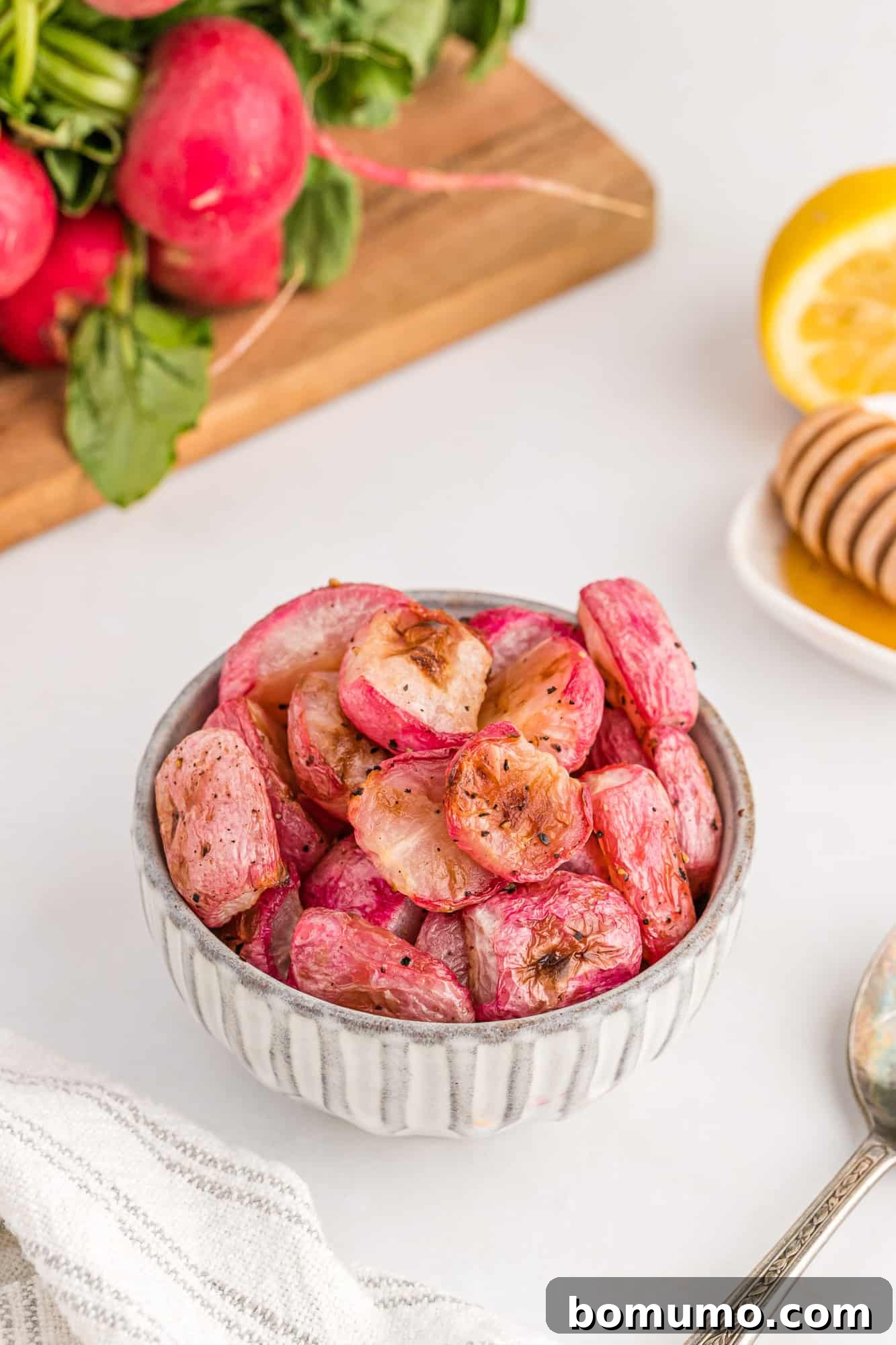 Radishes in a bowl with more in the background along with fresh lemon and honey, suggesting optional enhancements.