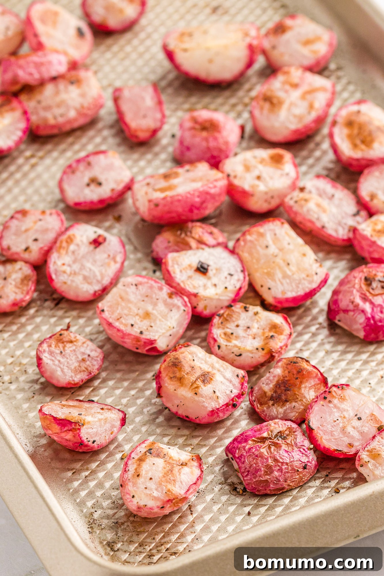 Freshly roasted radishes on a sheet pan, showing their tender, caramelized texture.