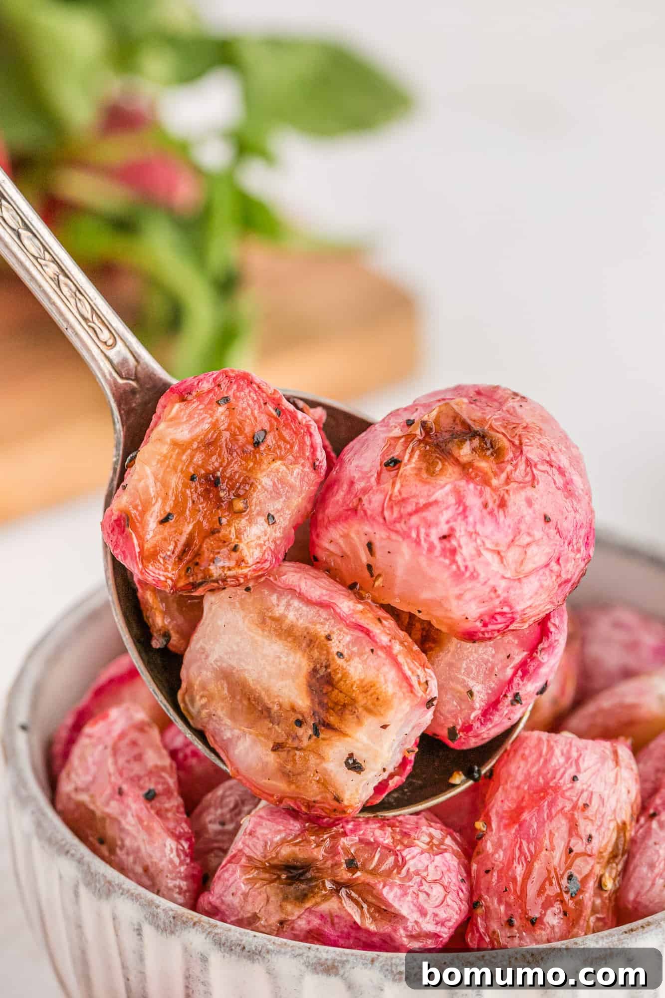 Roasted radish halves neatly presented on a serving spoon, highlighting their tender texture and appealing color.