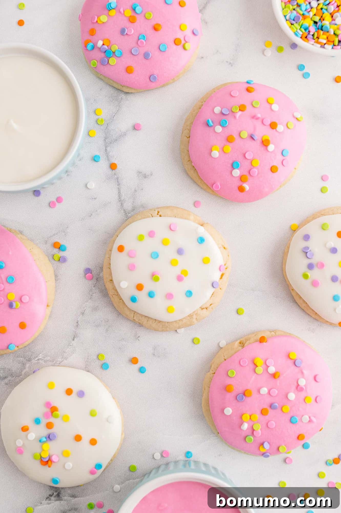 Overhead view of pink and white lofthouse style cookies with colorful sprinkles.