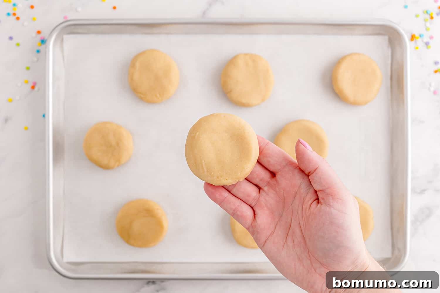 Flattened unbaked cookie in a hand.