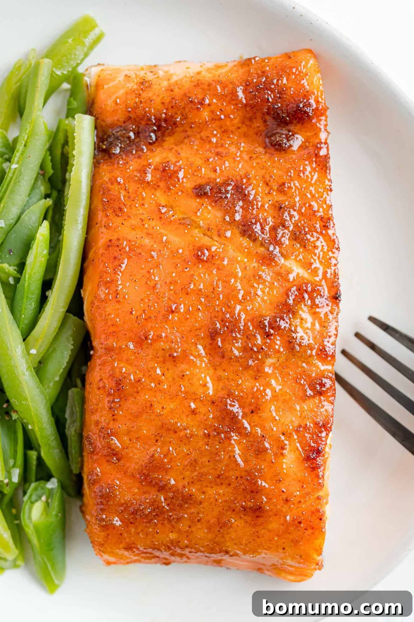 A perfectly plated BBQ salmon dinner, complete with fresh green beans. An inviting overhead view of a plate featuring a delicious BBQ salmon fillet, perfectly cooked and served alongside vibrant green beans.
