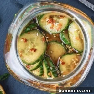 Korean pickles in a small glass jar, flecks of red pepper visible.