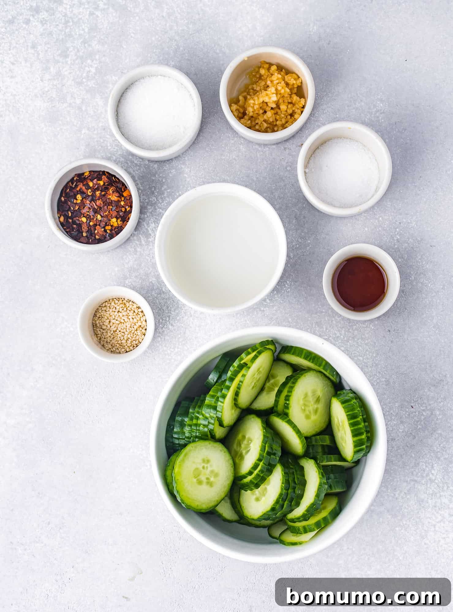 Ingredients needed in separate bowls including sliced cucumber.