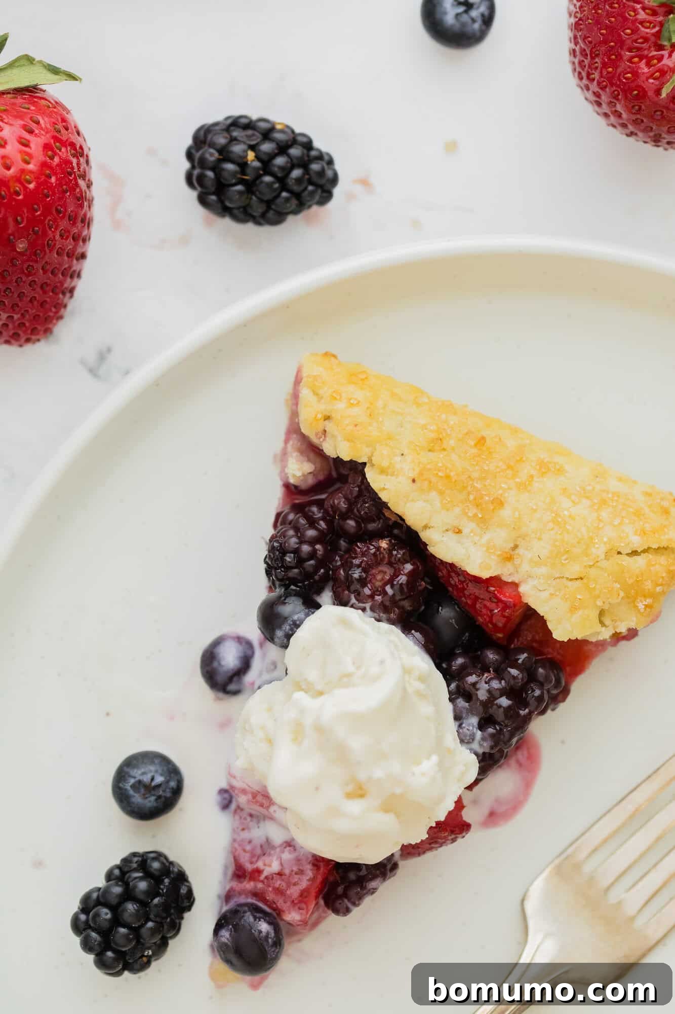 A single slice of berry galette, topped with a scoop of vanilla ice cream, elegantly presented on a plate.
