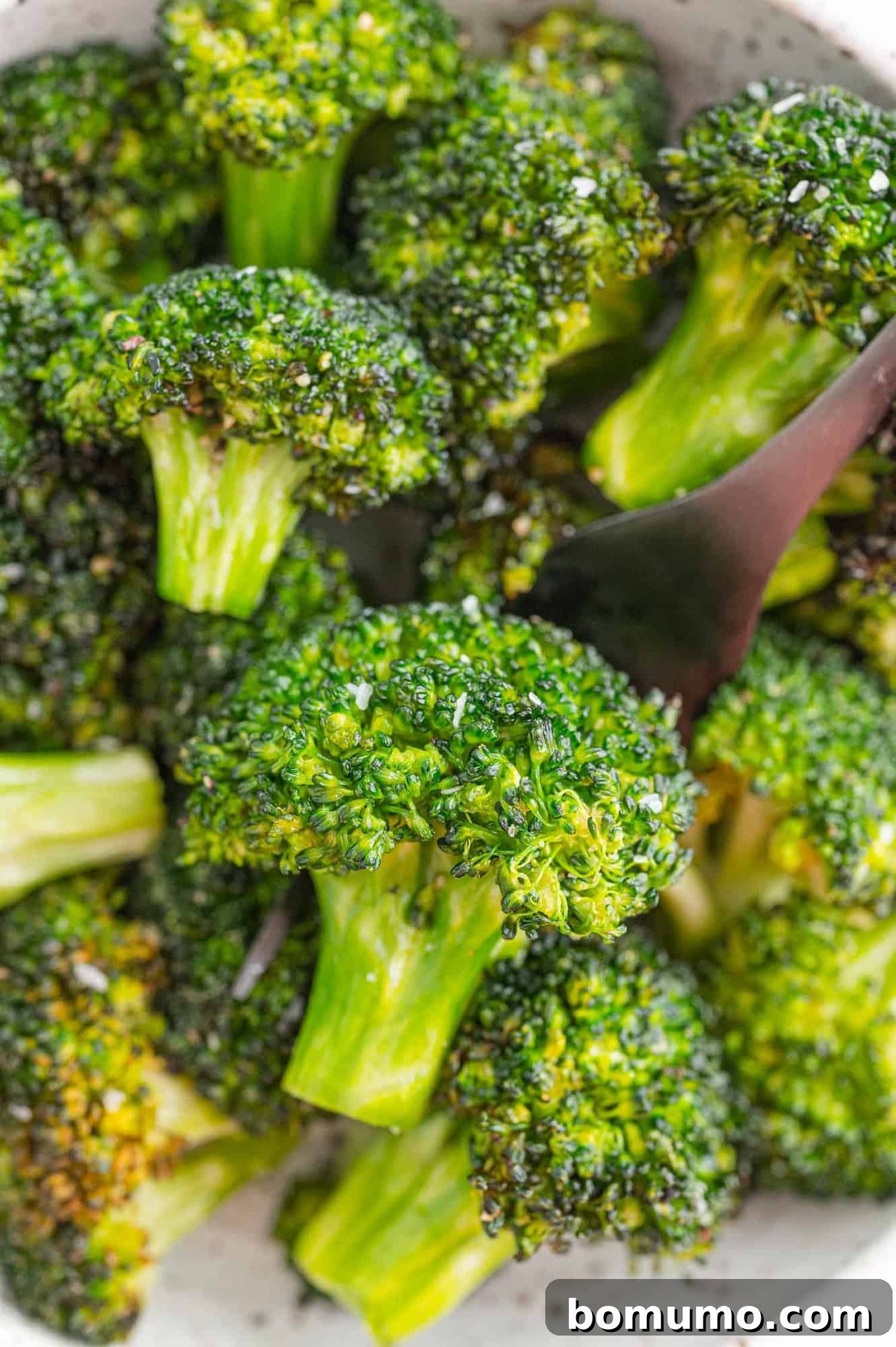 A vibrant pile of perfectly cooked, crispy air fryer broccoli florets in a white serving bowl, ready to be enjoyed.