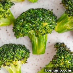 Florets of air fryer broccoli on white background, perfectly cooked and lightly browned.