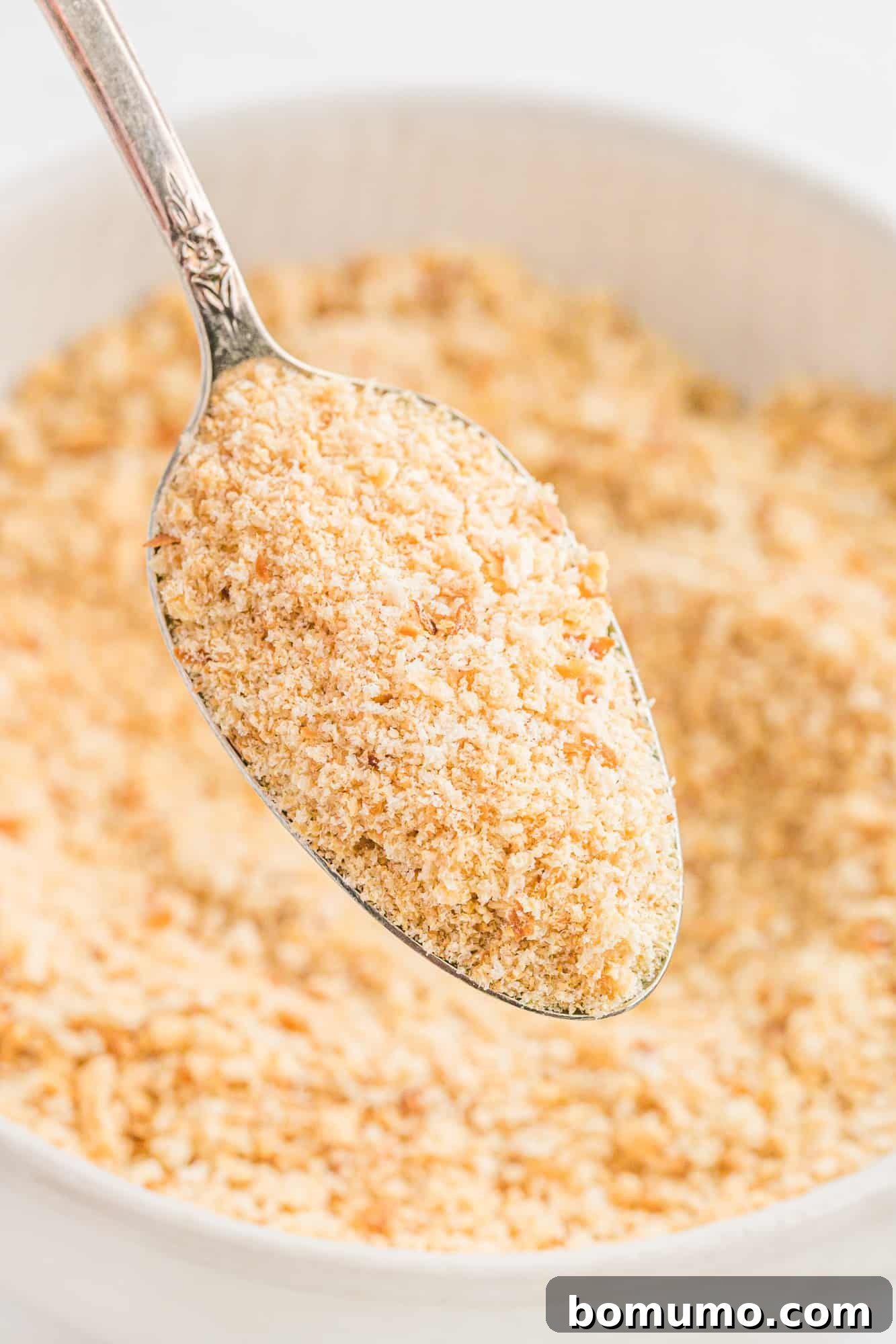 Homemade Bread crumbs on a spoon over a bowl.