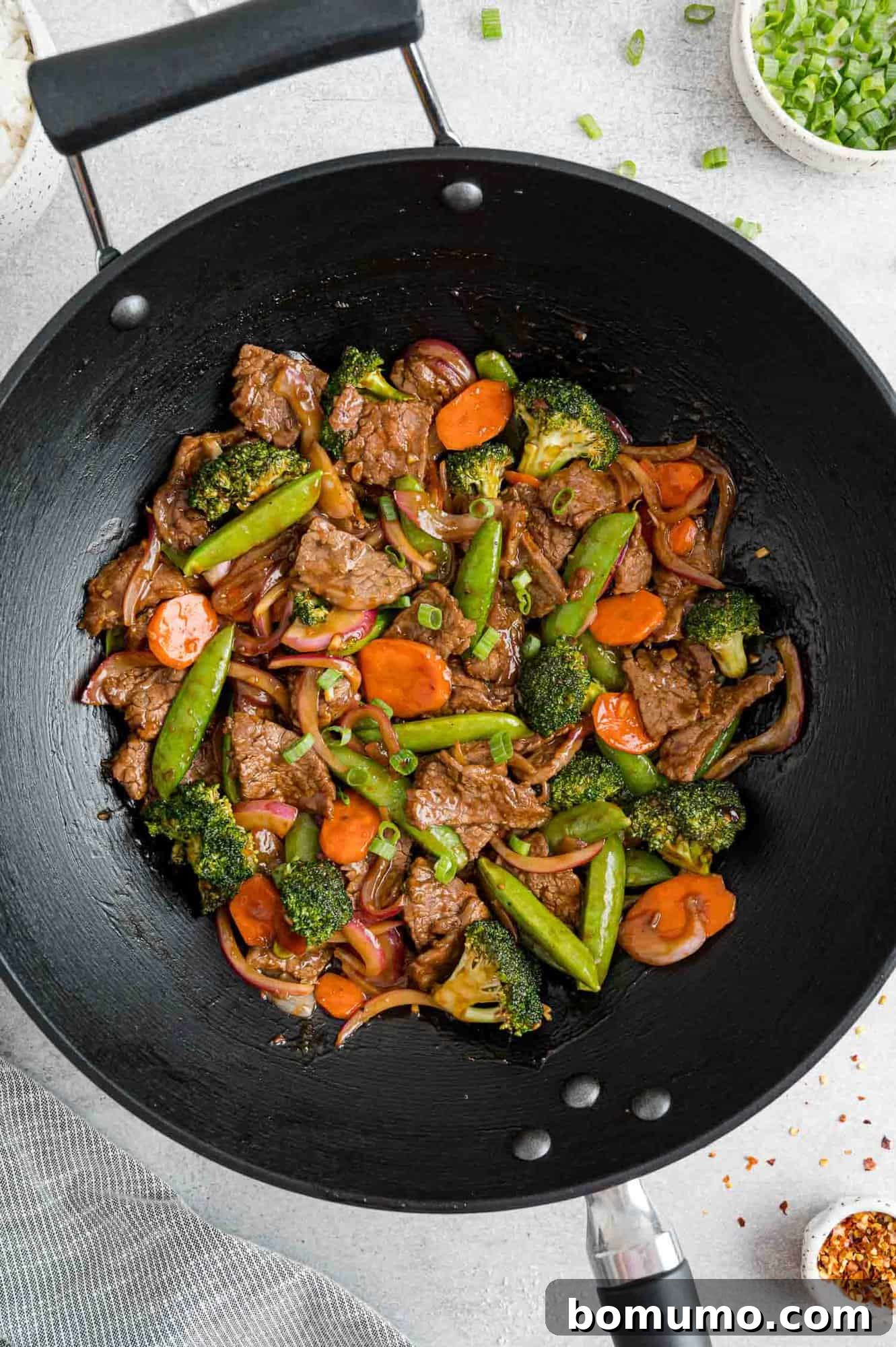The completed stir-fry, rich with beef and vegetables, glistening with sauce in a black wok.