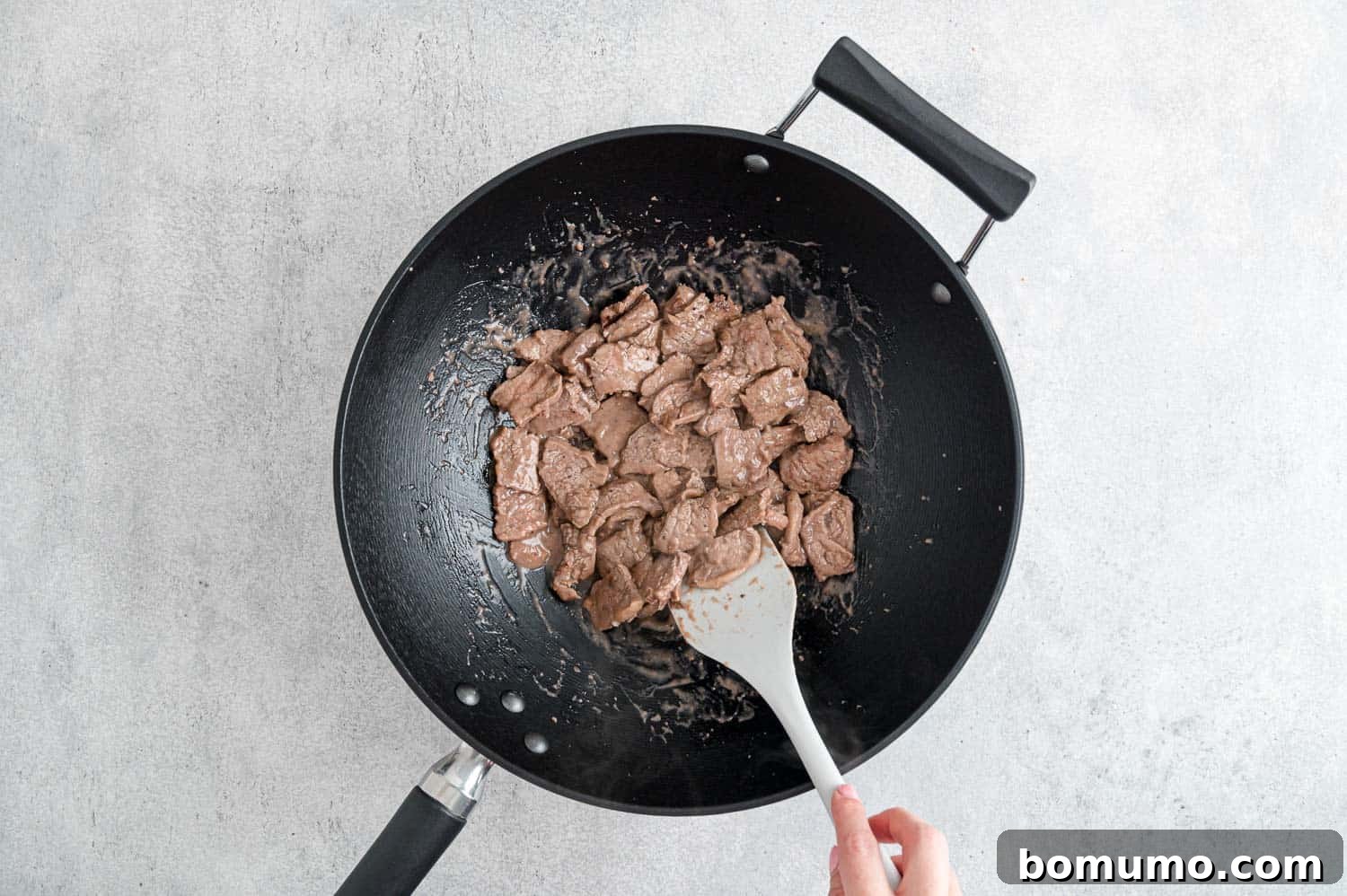 Beef being expertly cooked in a hot wok, ensuring a perfect sear.