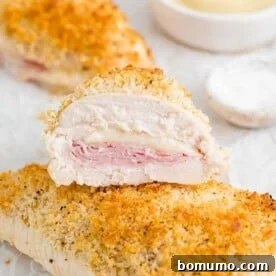 A perfectly baked chicken cordon bleu, sliced in half to beautifully showcase its mouth-watering ham and Swiss cheese filling.