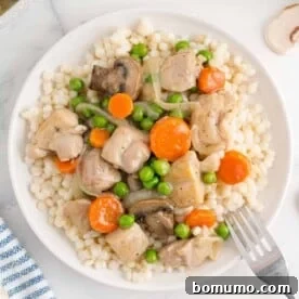 Flavorful tarragon chicken and mixed vegetables served over a bed of light, fluffy couscous, creating a wholesome and inviting plate.
