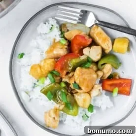 A vibrant sweet and sour chicken stir fry, artfully arranged on a plate with steamed rice, showcasing its colorful ingredients.