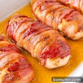 Crispy bacon-wrapped chicken breasts, cooked to a golden brown and glistening with savory juices in a baking dish.