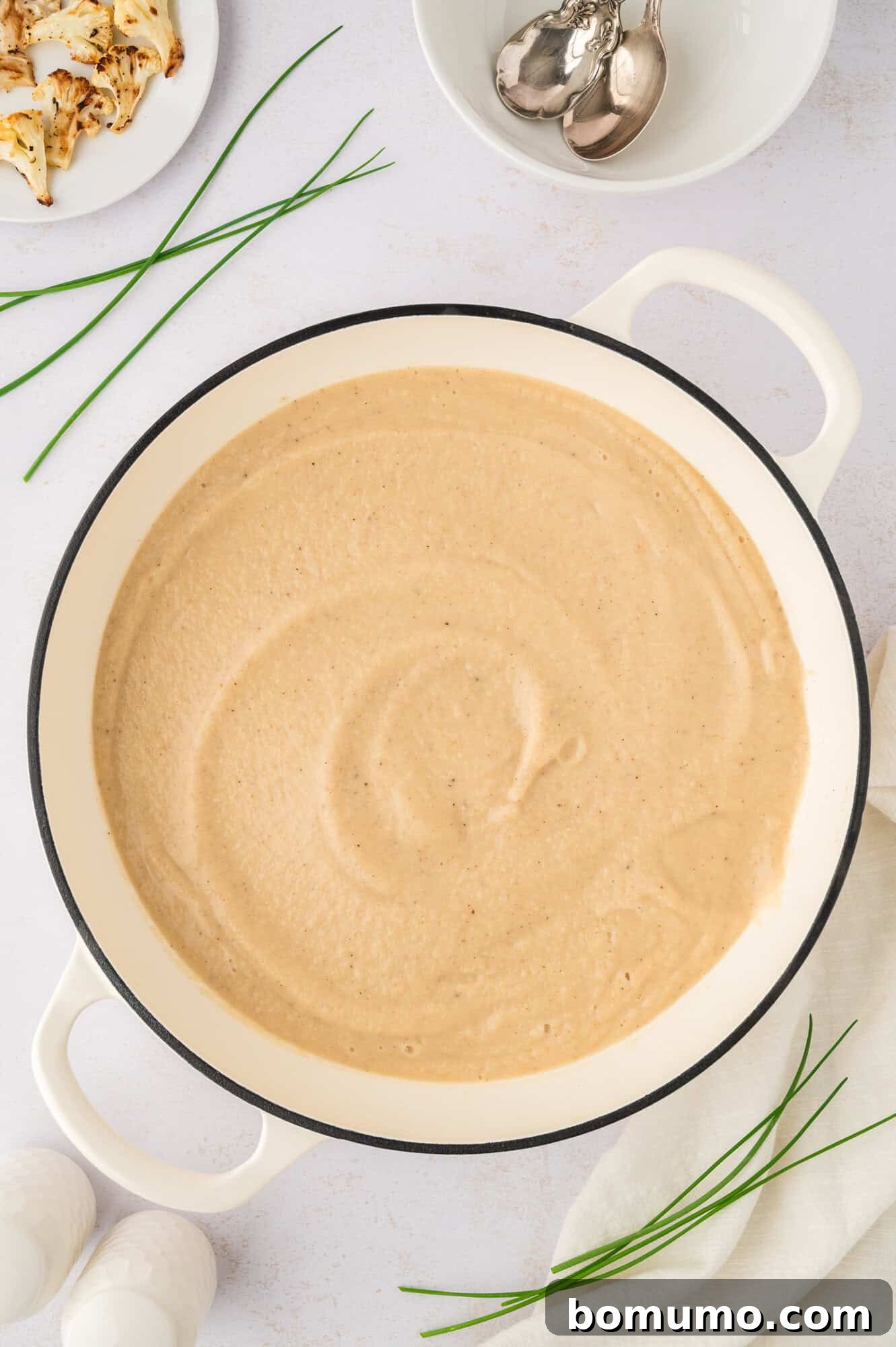 The finished, perfectly puréed roasted cauliflower soup in a Dutch oven, showcasing its smooth, creamy consistency.