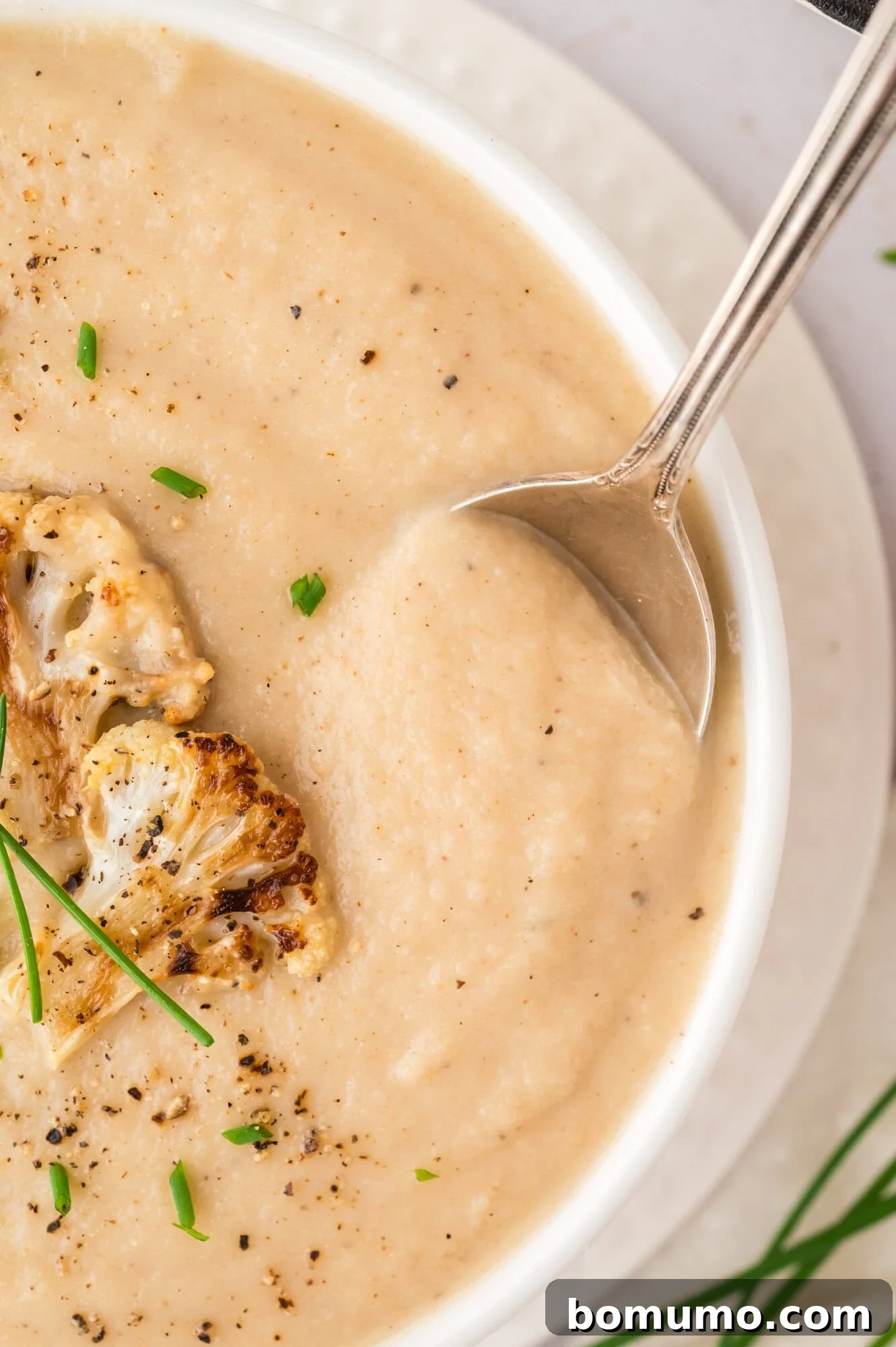 A spoonful of rich and creamy roasted cauliflower soup, showcasing its smooth texture.