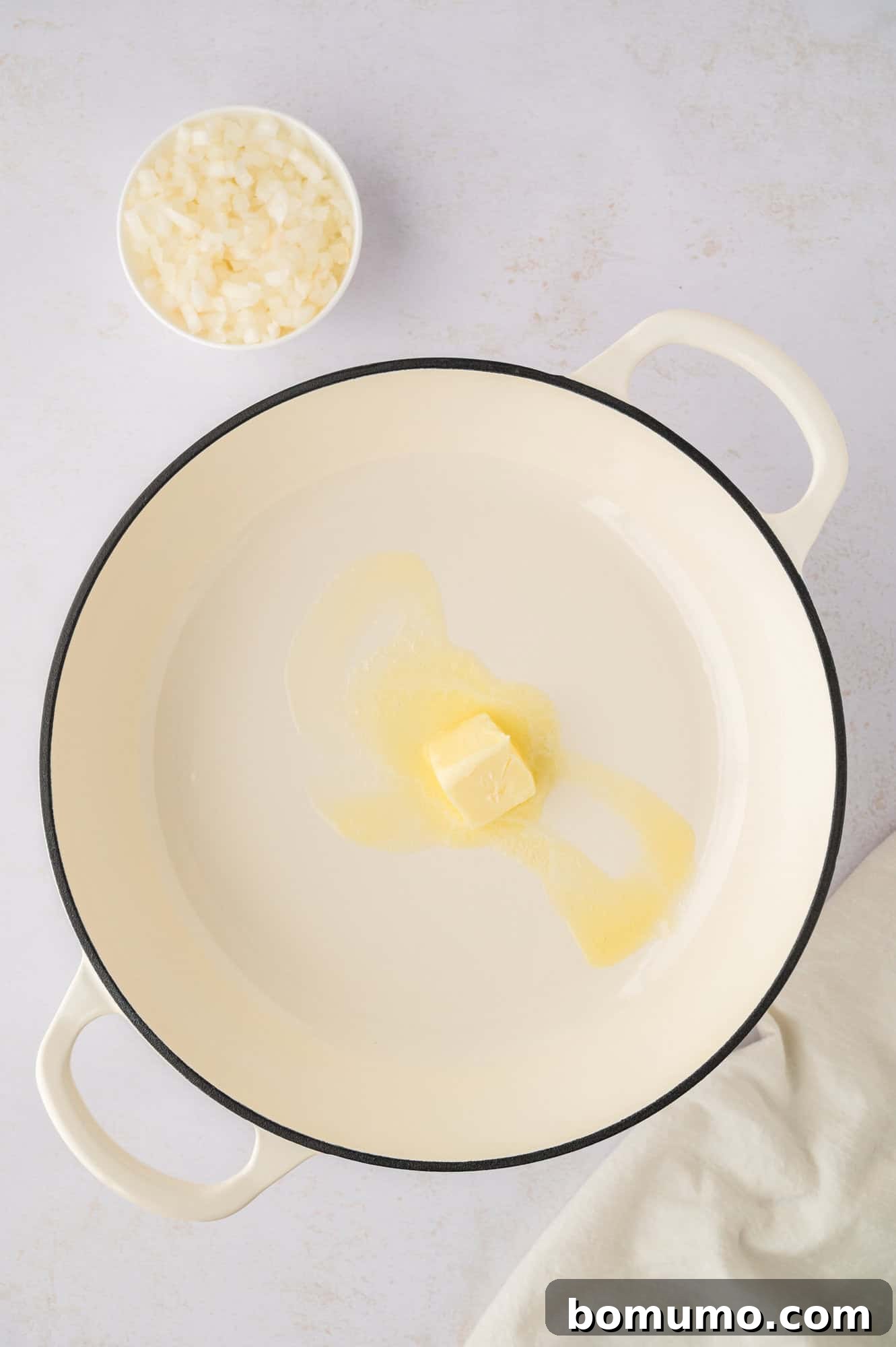 Unsalted butter gently melting in a preheated Dutch oven, forming a rich base for the soup's aromatics.