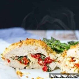 Closeup front view of a stuffed chicken breast sliced in half, served on a plate with asparagus.