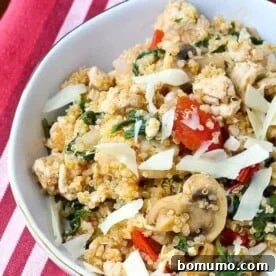 Overhead view of a quinoa recipe in a round white dish, featuring ground turkey, kale, mushrooms, and tomatoes.