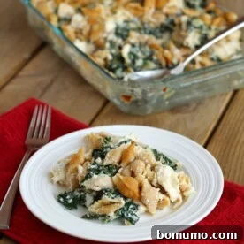A serving of comforting chicken and kale casserole on a white plate, with the clear glass casserole pan visible in the background.