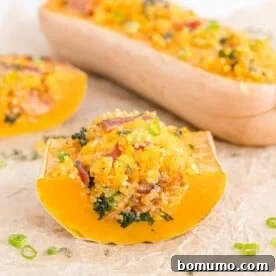 Stuffed butternut squash cut to show a delectable filling of quinoa, bacon, and kale.