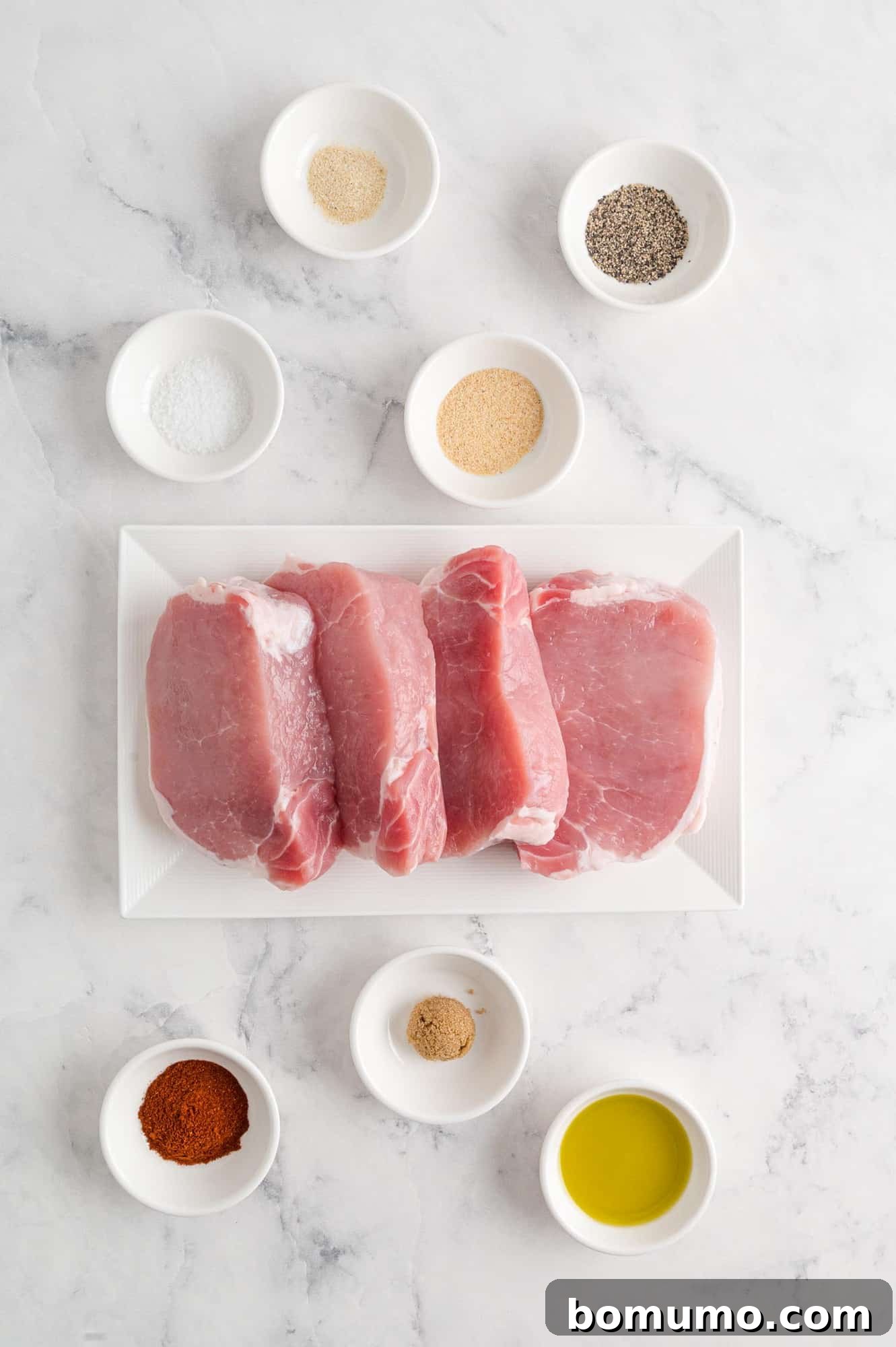 Overhead view of fresh ingredients including uncooked pork chops, ready for preparation.