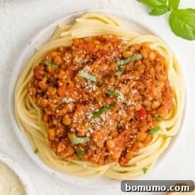 A rich vegan bolognese sauce, made with lentils and quinoa, served generously atop a bed of spaghetti.