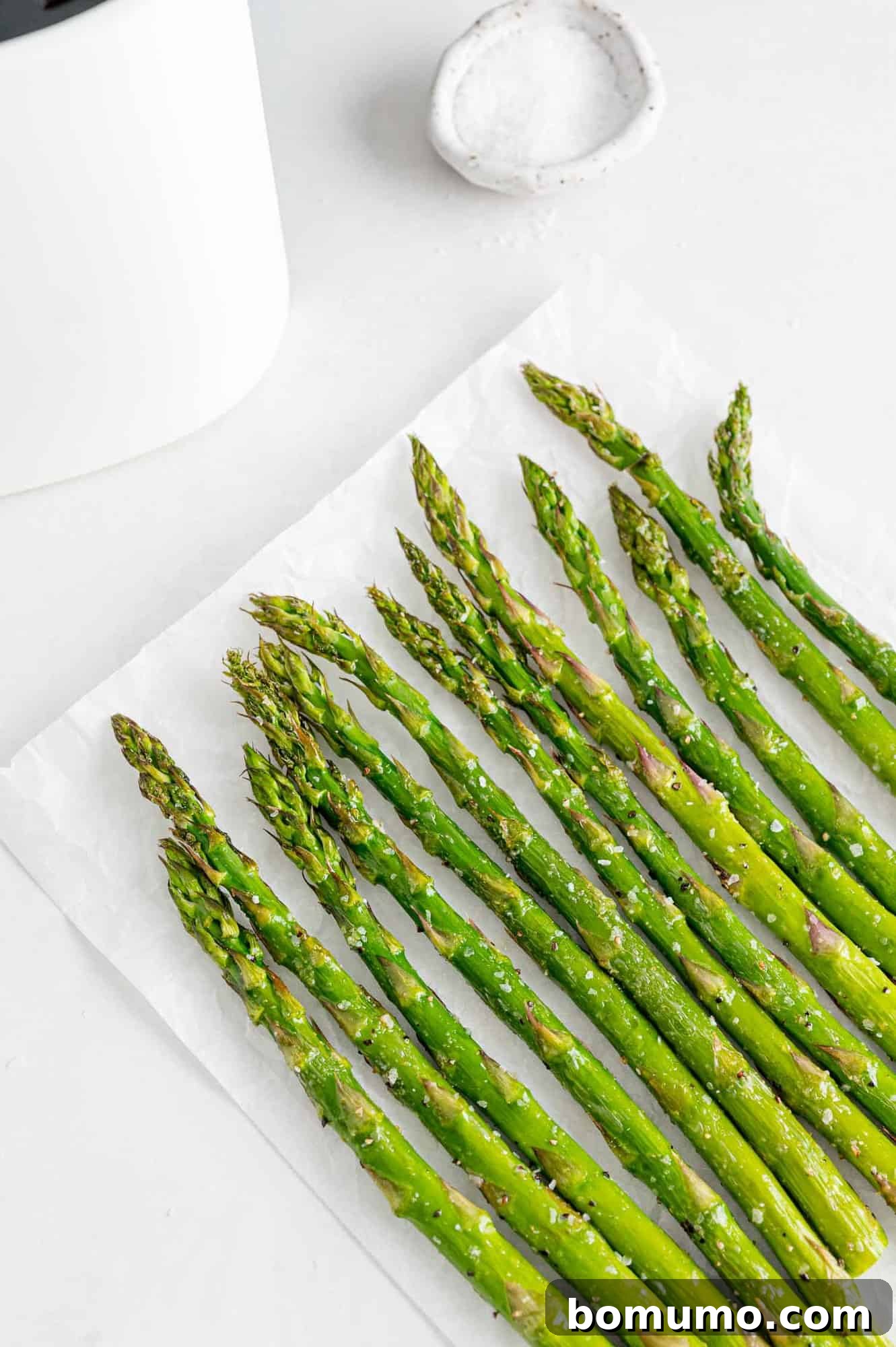 A serving of vibrantly green air fryer asparagus, artfully arranged on a plate with a soft focus background, emphasizing its freshness and culinary appeal.