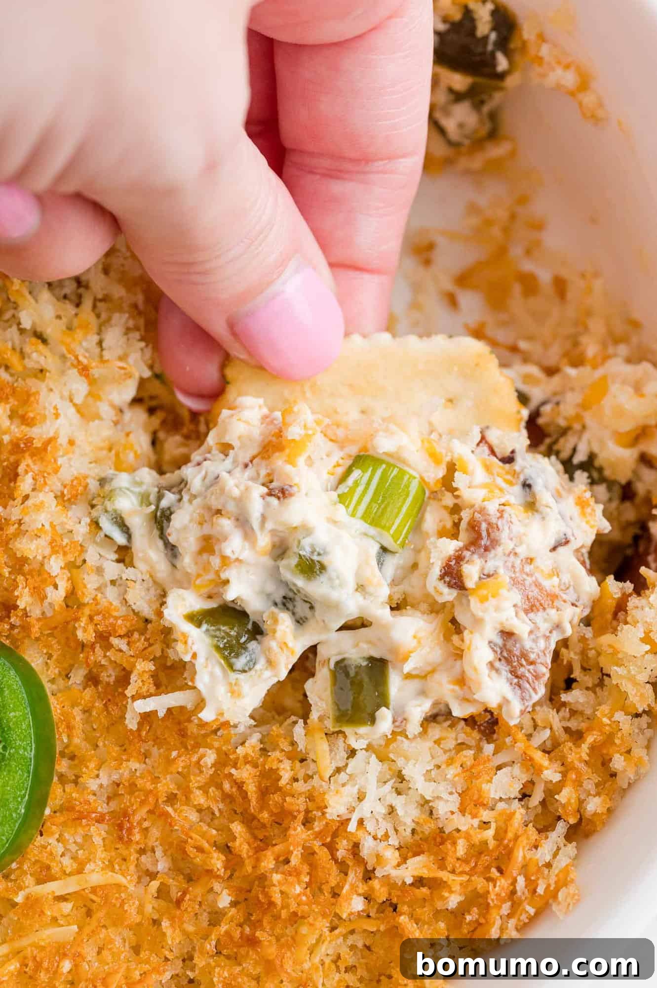 Popper dip on a cracker. A close-up shot of the creamy dip loaded onto a crisp cracker.