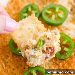 Jalapeño popper dip on a cracker. A savory, creamy dip with a golden topping.